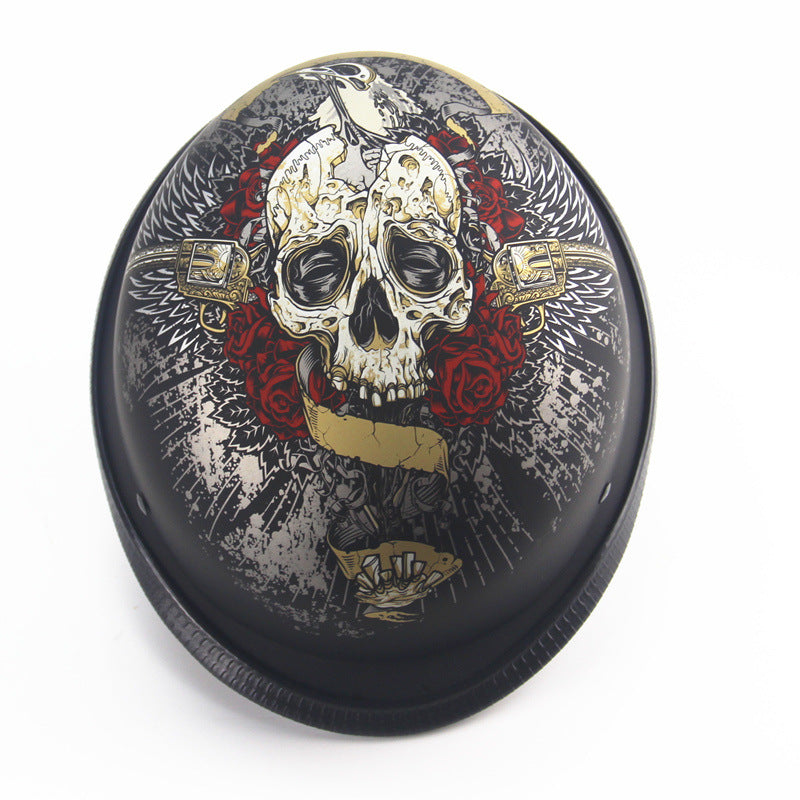 This Skull Cap Motorcycle Helmet in matte black is DOT Approved and showcases intricate artwork featuring a skull, roses, and wings adorned with gold accents against a sleek background, epitomizing the style of the Skull Cap Motorcycle Helmet.