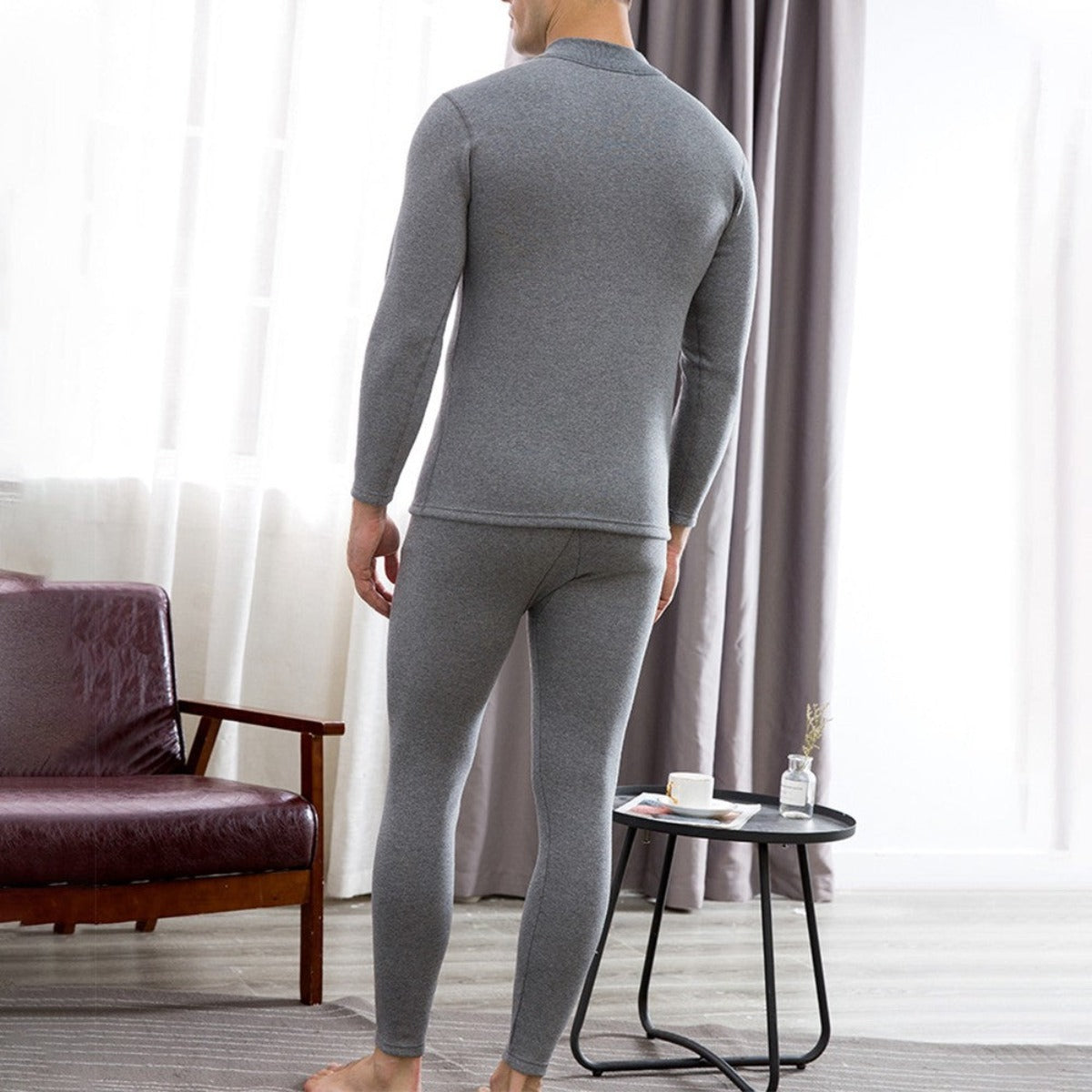 A man in Men's Soft Winter Thermal Underwear - Light Gray standing in front of a couch.