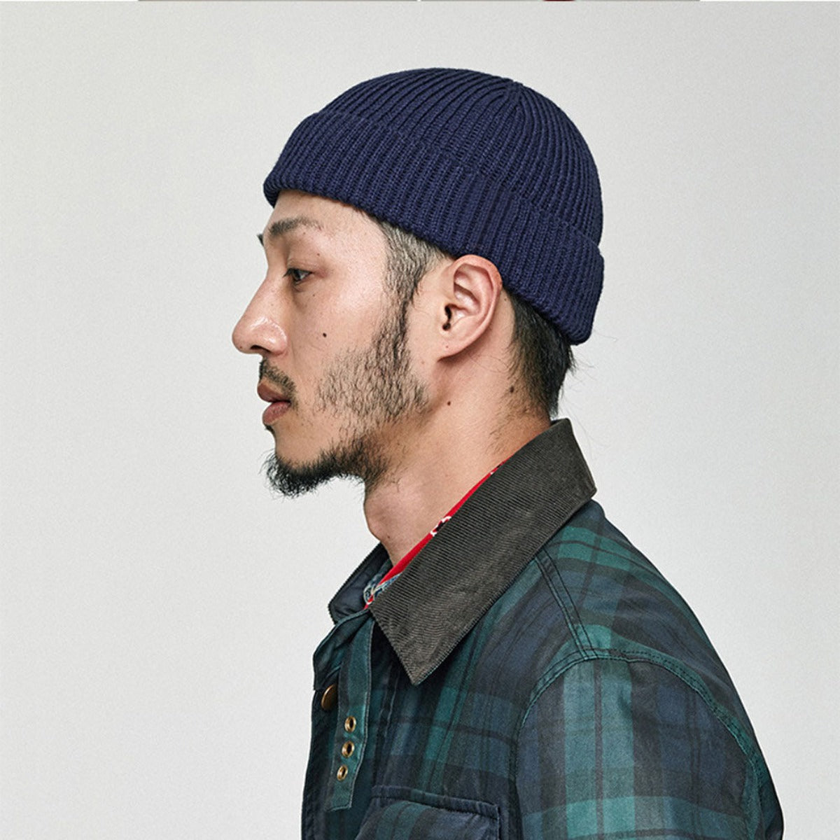 A man in a plaid shirt is wearing a Wool Knitted Skull Cap Beanie.
