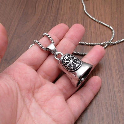 A hand holding a Stainless Steel Viking Compass Gremlin Bell with a snowflake design on a chain.
