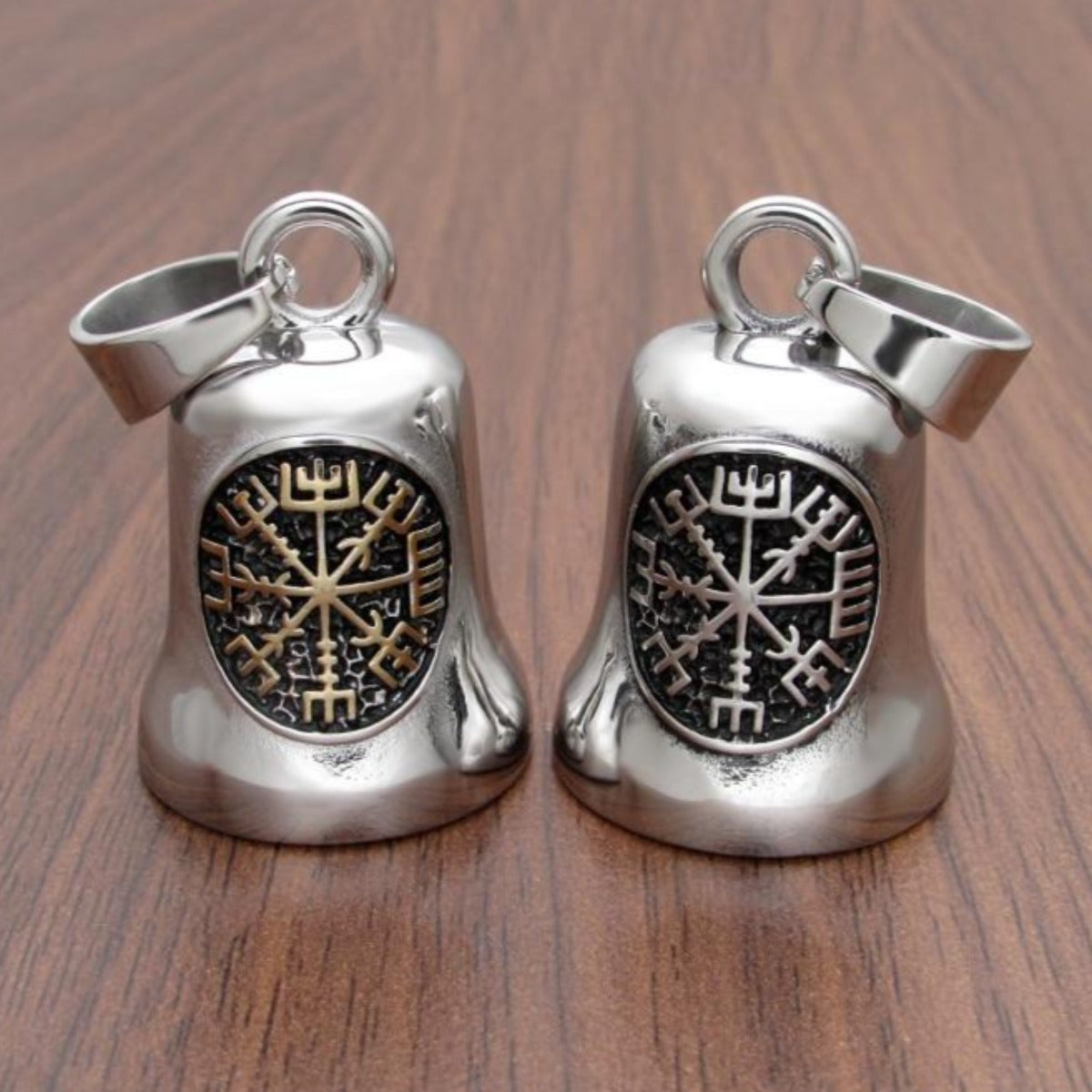 Two Stainless Steel Viking Compass Gremlin Bells with snowflake designs on a wooden surface.