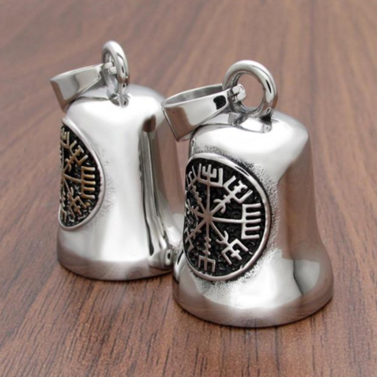 Pair of silver-colored Stainless Steel Viking Compass Gremlin Bell with intricate snowflake designs on a wooden surface.