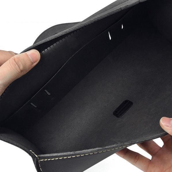An open empty black Leather Round Saddle Bag held by a person against a white background.