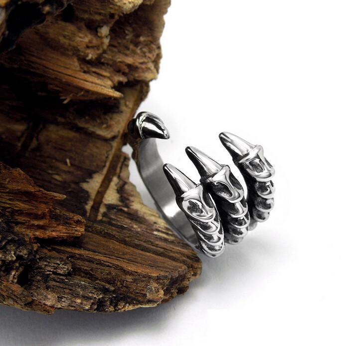 A Stainless Steel Dragon Claw Biker Ring with claws on top of a piece of wood.