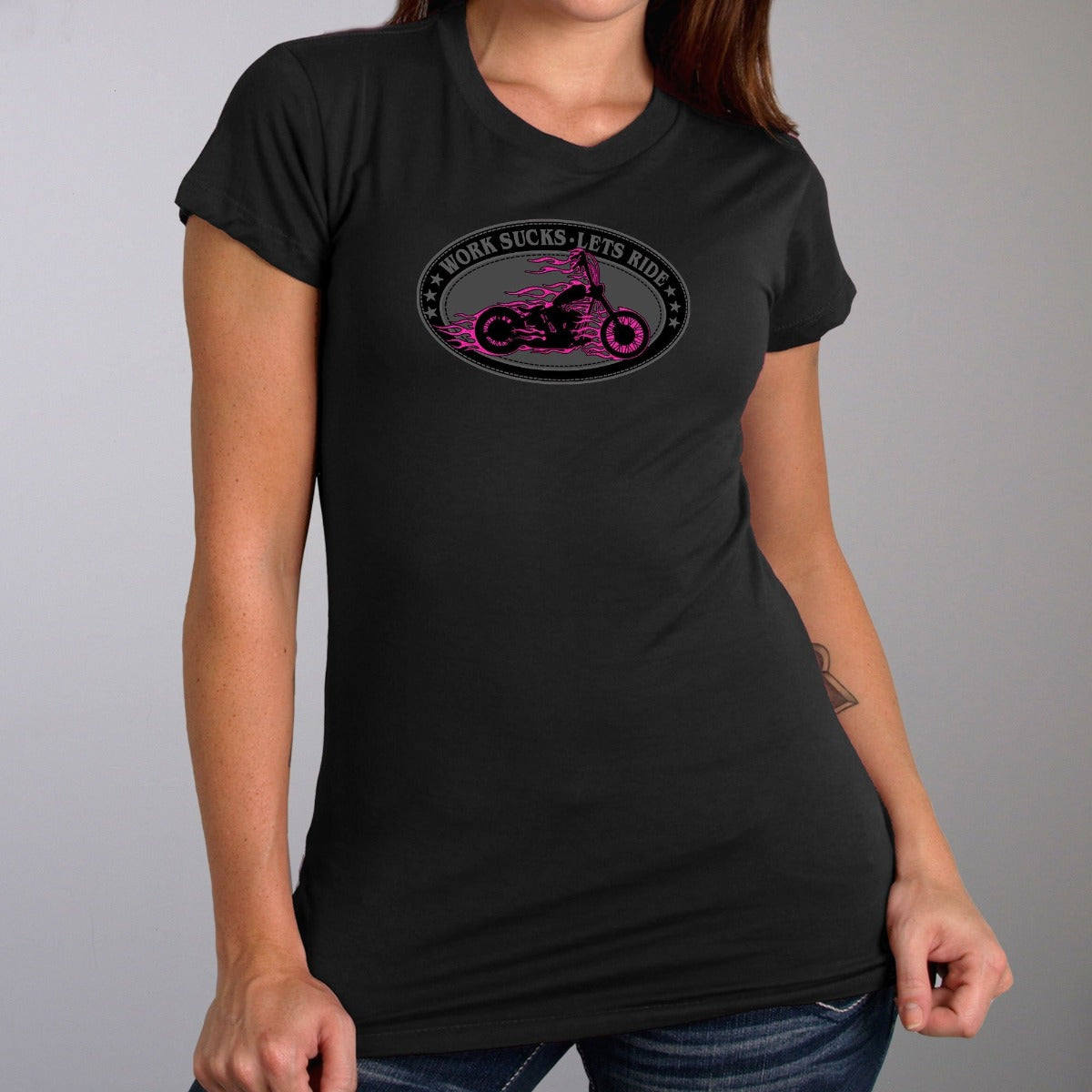 A person is wearing the Hot Leathers Women's Work Sucks Oval Tee Shirt, which is black with a pink motorcycle graphic, metallic purple flames, and the bold text "Work Sucks, Let's Ride.