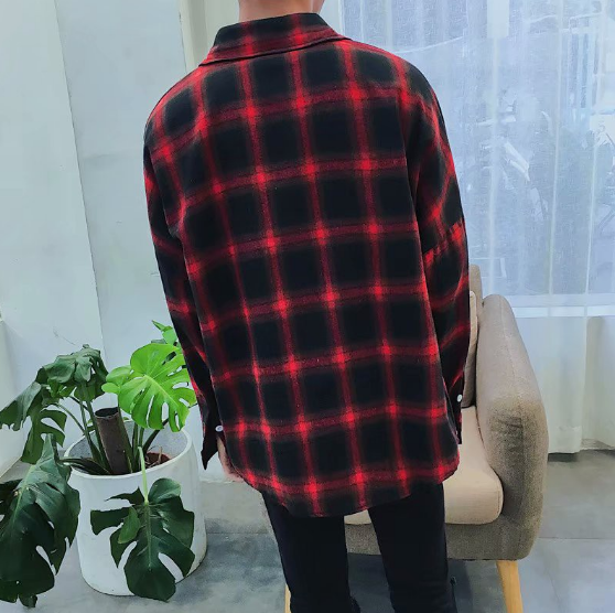 A person in a Men's Classic Plaid Flannel Shirt (Red/Black) stands indoors next to a potted plant and a chair.