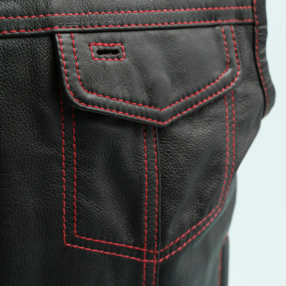 Close-up of a black milled cowhide leather First Manufacturing Men's The Cut Motorcycle Leather Vest pocket with red stitching.