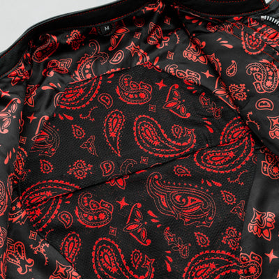 A close-up view of fabric with a First Manufacturing Men's The Cut Motorcycle Leather Vest, Black/Red paisley club style pattern.