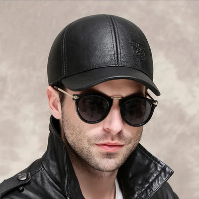 Wearing an ALR™ Genuine Leather Eagle Baseball Cap made from cowhide, a person stylishly pairs it with round sunglasses and a sleek black leather jacket against a neutral background.