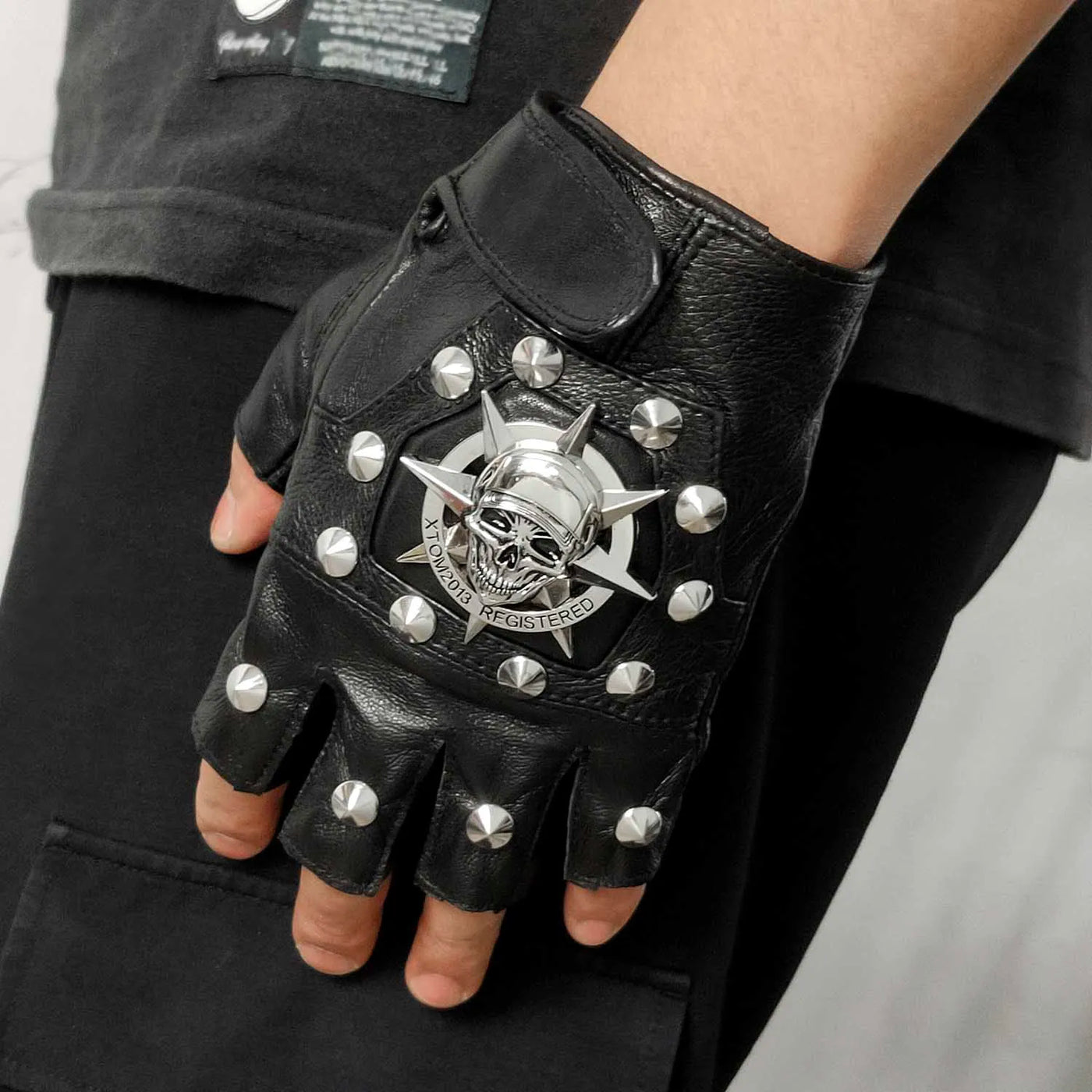A man wearing a pair of Men's Skull Steampunk Biker Leather Gloves with studs on them.