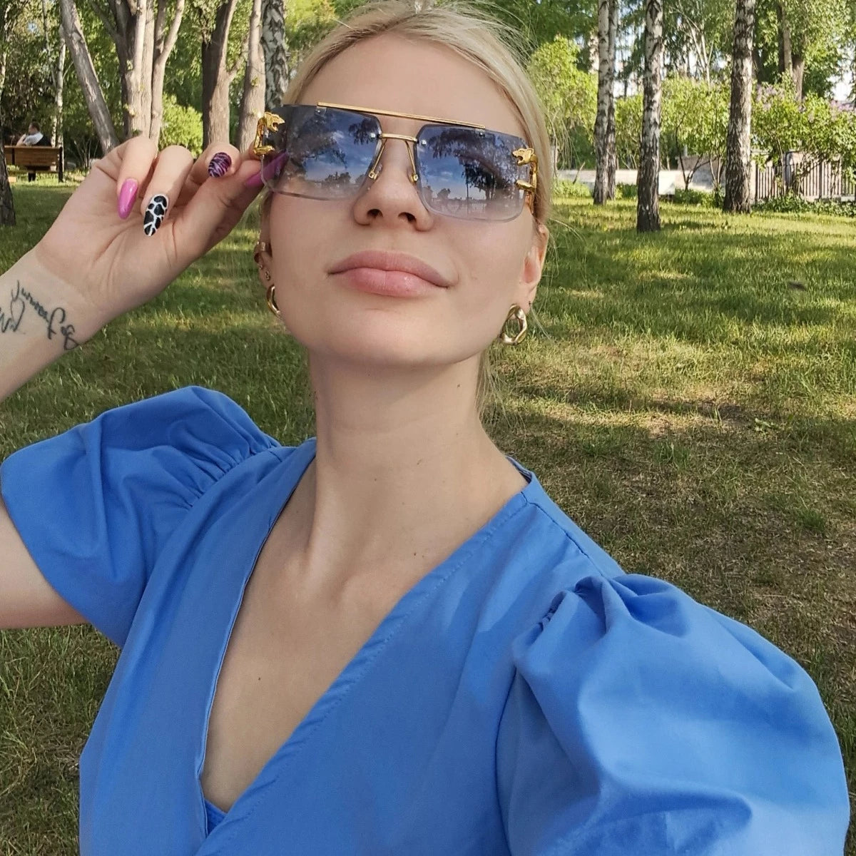 A woman wearing Retro Rimless Steampunk UV400 sunglasses in a park.