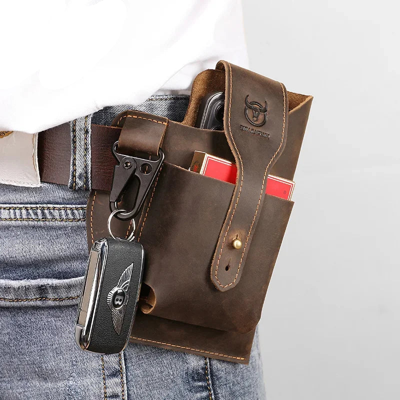 The ALR™ New Men's Leather Waist Bag, ideal for motorcycle riders, features a rugged brown leather design with a snap closure perfect for jeans. It securely holds a phone, red box, and silver key fob using a clip.