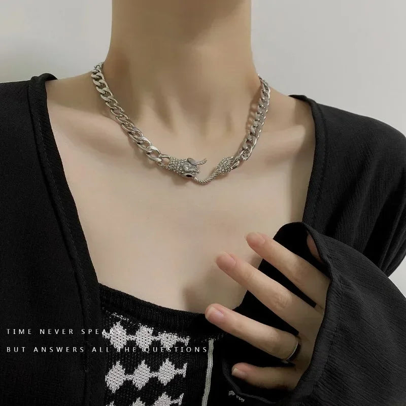 Sporting an edgy vibe, a person wears the ALR™ Vintage Punk Viper Necklace in silver with snake and scorpion motifs. A black top with a subtle checkered pattern stands out against the neutral backdrop.