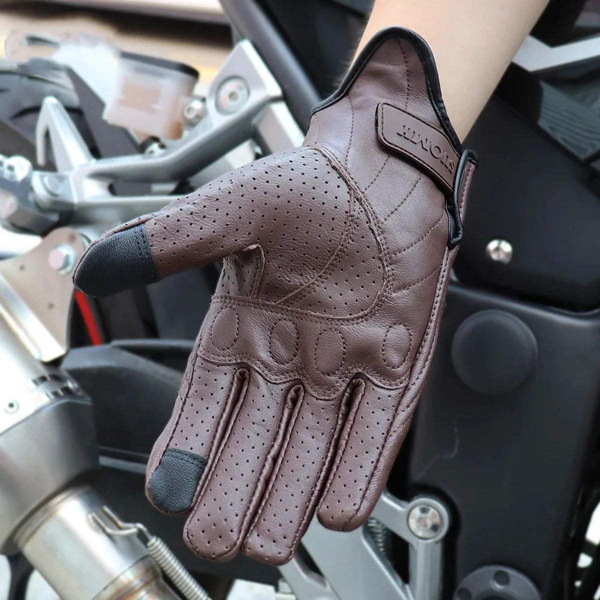 A hand wearing Alr™ Vintage Goatskin Full-Finger Motorcycle Gloves, known for their shockproof protection, is positioned confidently on a motorcycle handlebar.