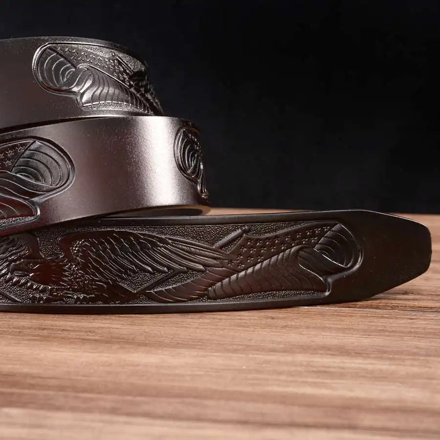 Close-up of the Alr™ Men's Leather Ratchet Belt, showcasing its intricate carved designs and automatic buckle as it rests elegantly on a wooden surface.