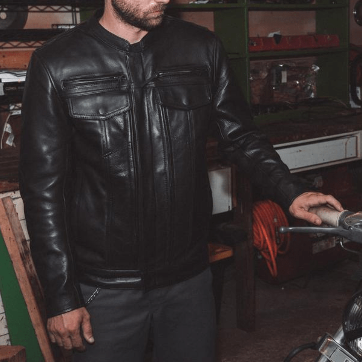A First Manufacturing Raider Leather Jacket in a high-quality leather motorcycle jacket next to a motorcycle.