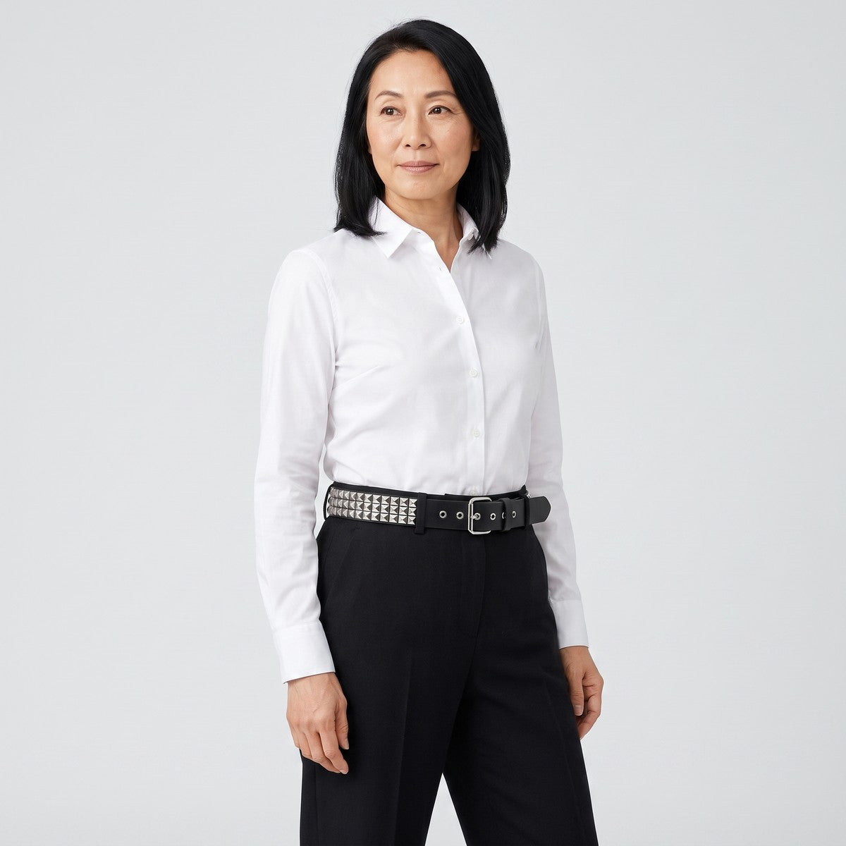 Pyramid studded belt worn with high waisted black trousers and a white shirt