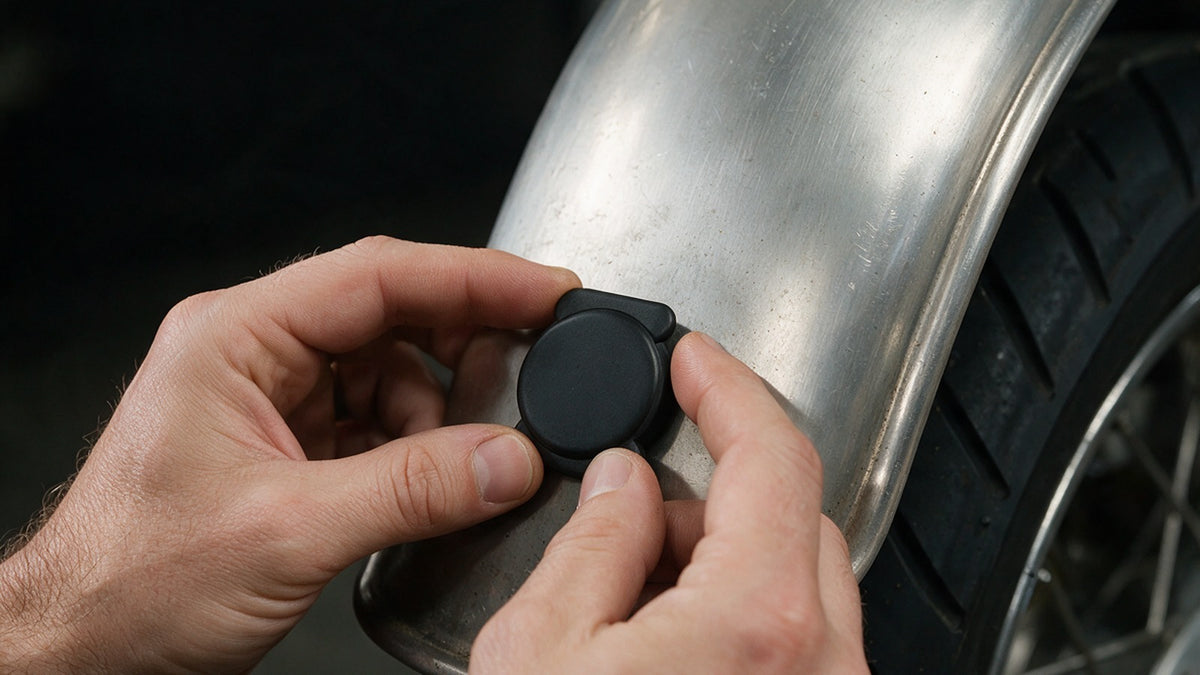 Pressing the magnetic Bluetooth finder tag onto a motorcycle fender