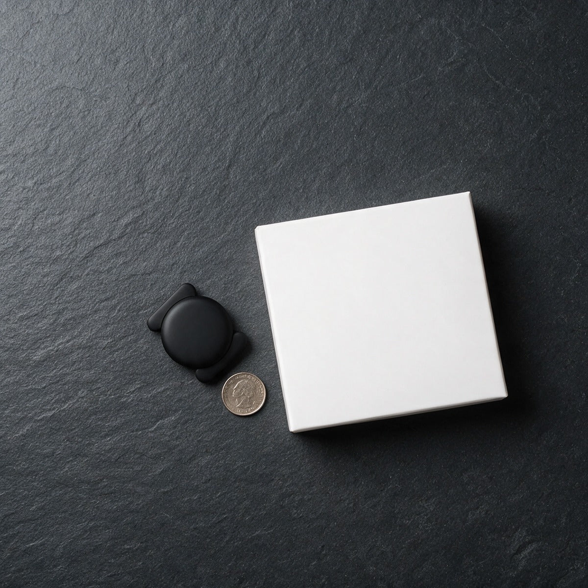 Stealth Bluetooth finder tag beside its box with a coin for scale
