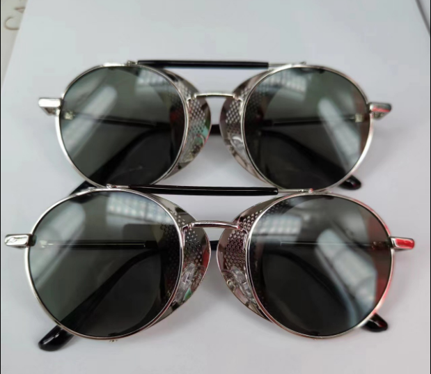 Two pairs of Bikers Retro Round Steampunk Glasses with metal frames and tinted lenses are stacked on top of each other on a white surface.