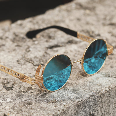 A pair of Rebellion Road Sunglasses in gold and blue, sitting stylishly on a rock.