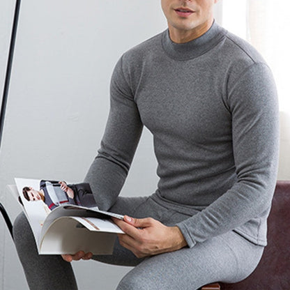 A man sitting on a chair holding Men's Soft Winter Thermal Underwear - Light Gray.