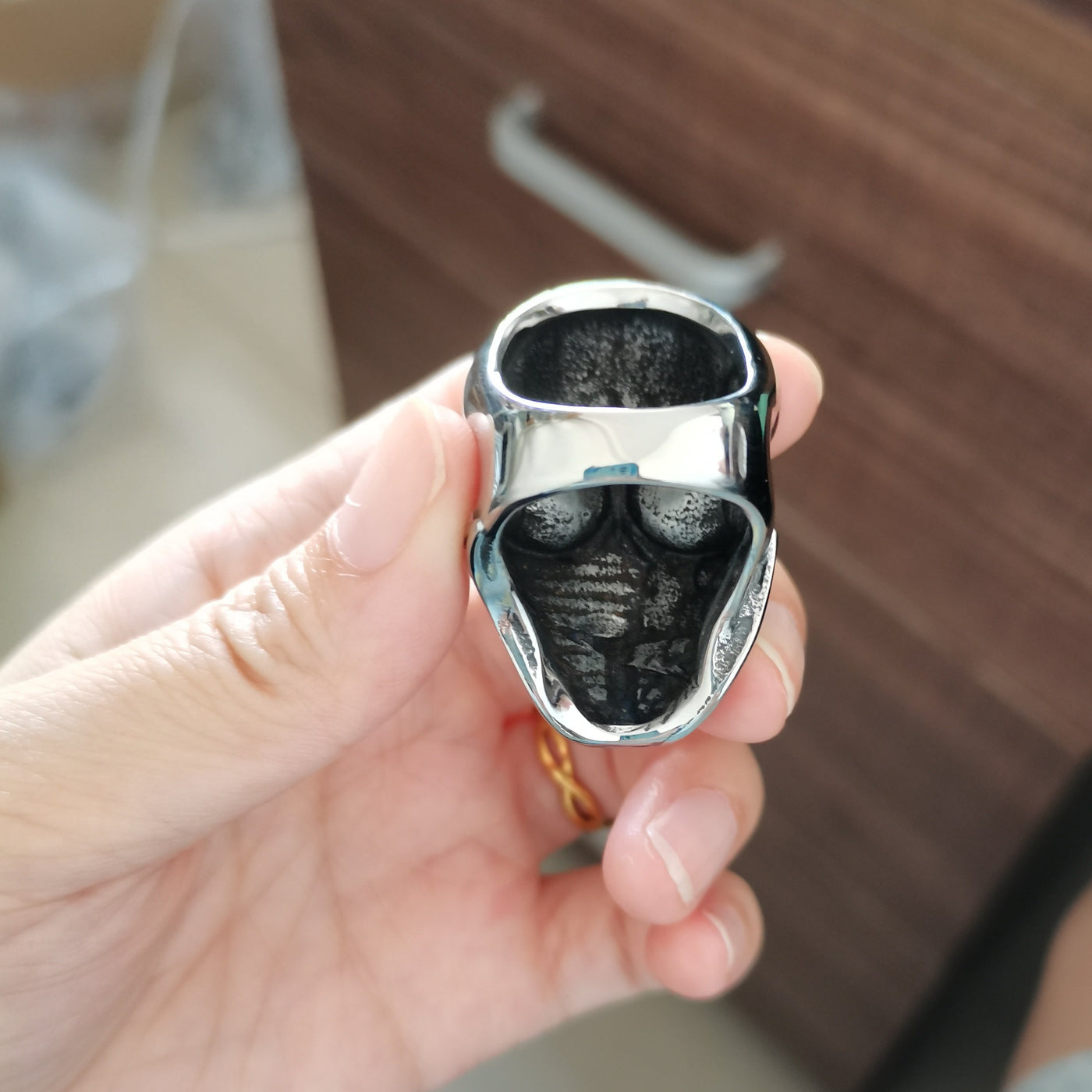 A person holding a Stainless Steel Men's American Flag Skull Ring, Silver Color.