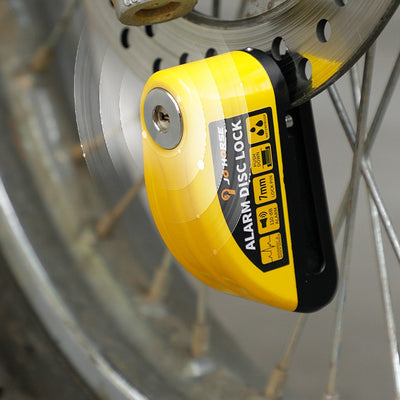A yellow Motorcycle Alarm Disc Lock is attached to a motorcycle's wheel.