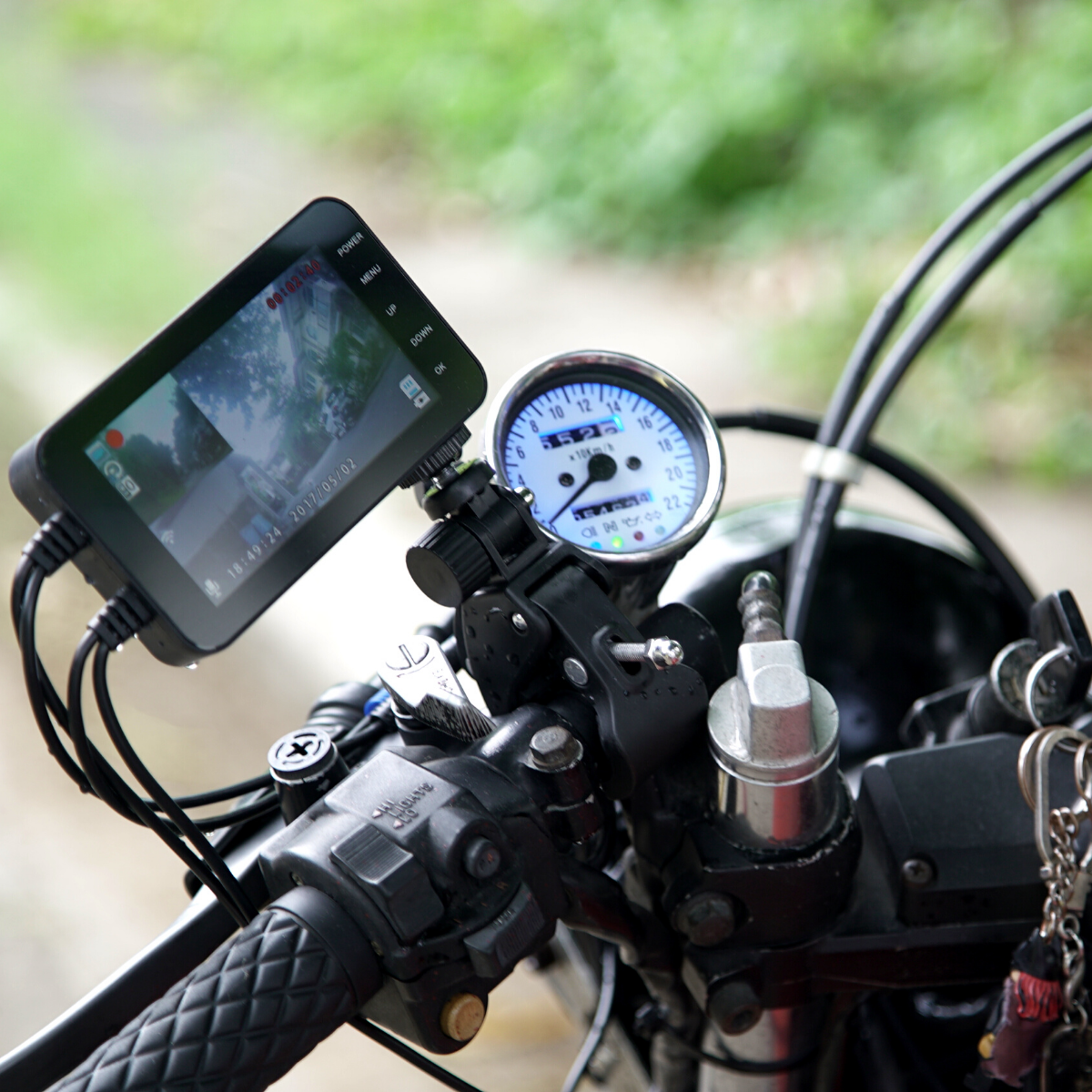 A compact Motorcycle Dual Lens Dash Camera Video Recorder 4 Inch HD 1080P with a water-resistant cell phone attached to the handlebars.