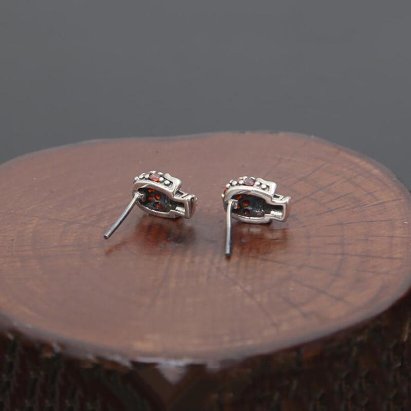 A pair of Fashion Skull Stud Earrings sitting on top of a wooden stump.