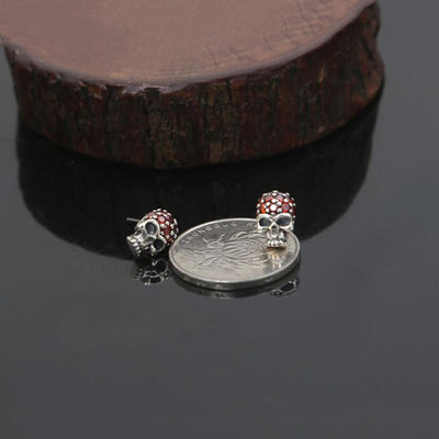A silver coin next to a Fashion Skull Stud Earring.