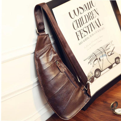 A brown Leather Sling Chest Bag featuring a one-shoulder strap, hanging on a wall.