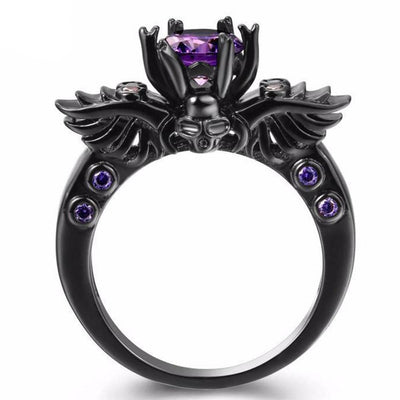 A black Vintage Skull Shaped Ring with an amethyst stone and wings.