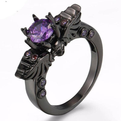 A Vintage Skull Shaped Ring with purple stones and a bat on it.