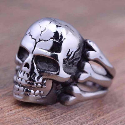 A Zinc Alloy Gothic Skull & Bones Biker Ring, Silver Tone on a wooden table.