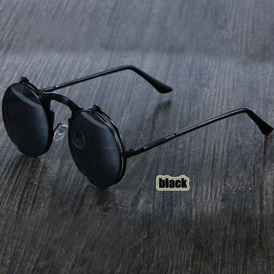 A pair of Steampunk Flip-Up Round Double Lens Sunglasses with a biker style on a wooden table.