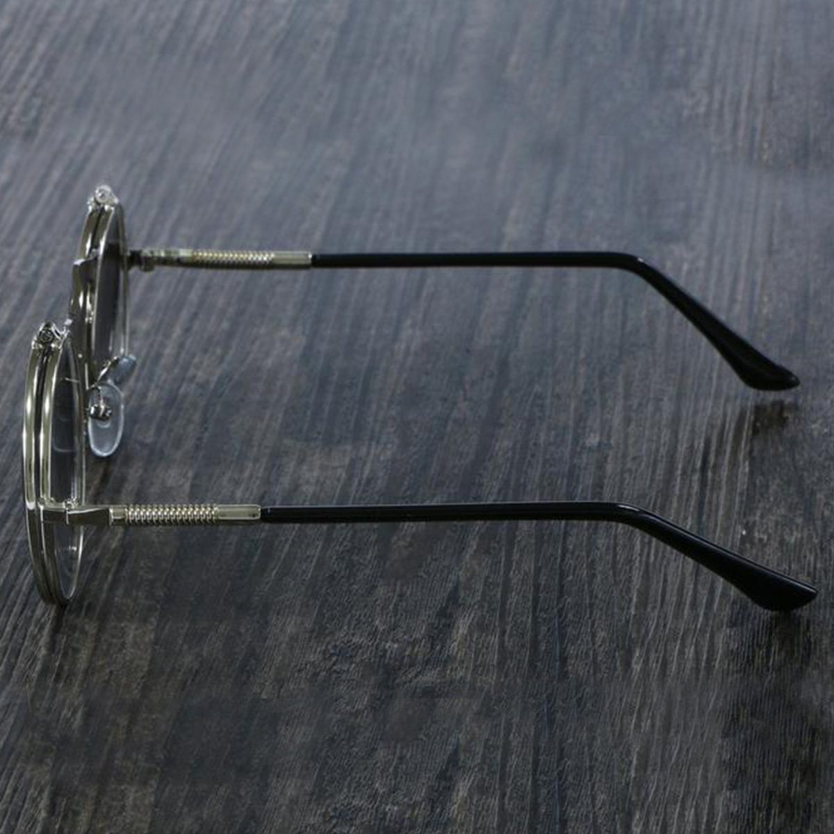 A pair of Steampunk Flip-Up Round Double Lens sunglasses on a wooden table.
