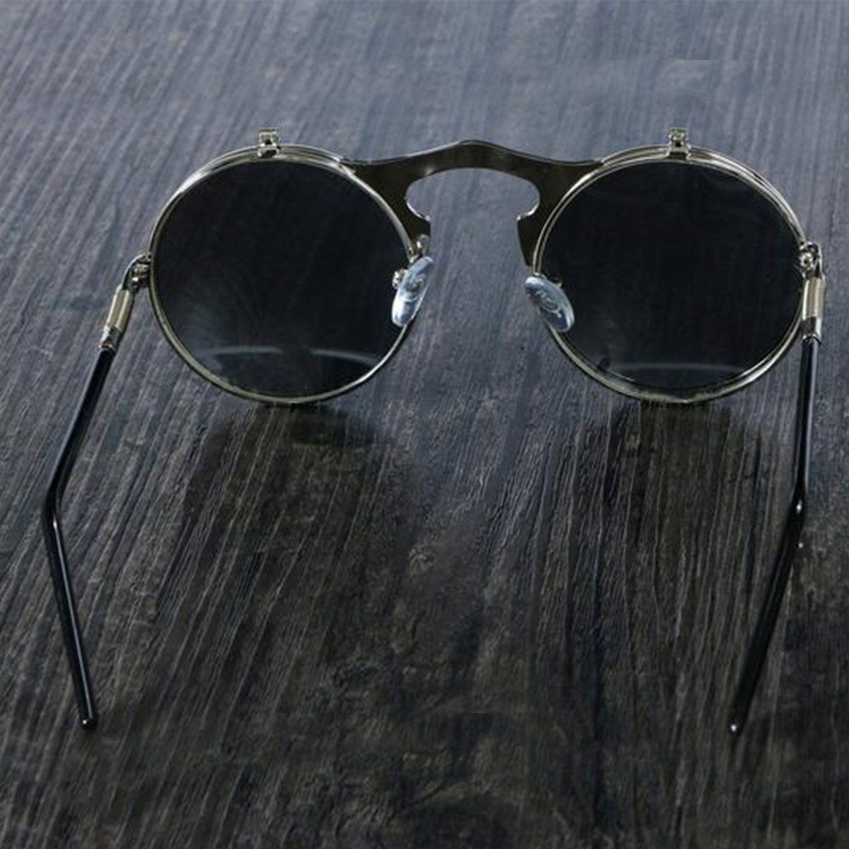 A pair of Steampunk Flip-Up Round Double Lens Sunglasses on top of a wooden table.