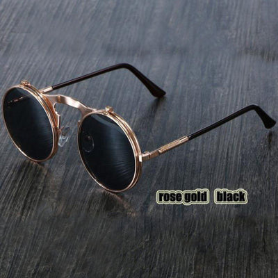 A pair of Steampunk Flip-Up Round Double Lens Sunglasses with black lenses on a wooden table.