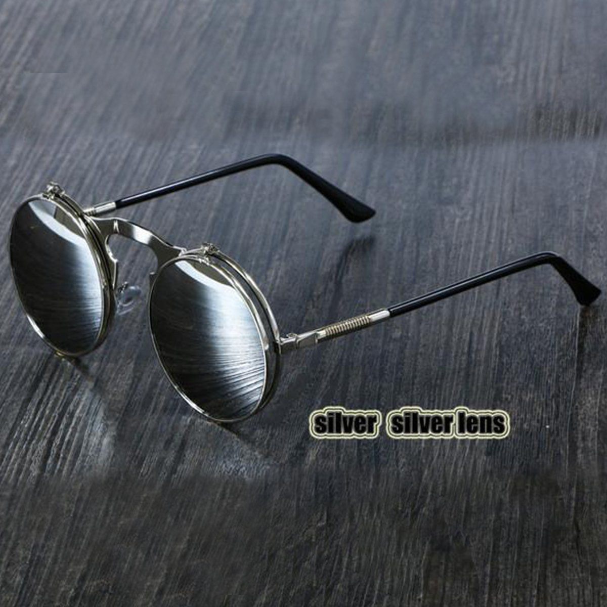 A pair of silver Steampunk Flip-Up Round Double Lens sunglasses on a wooden table.