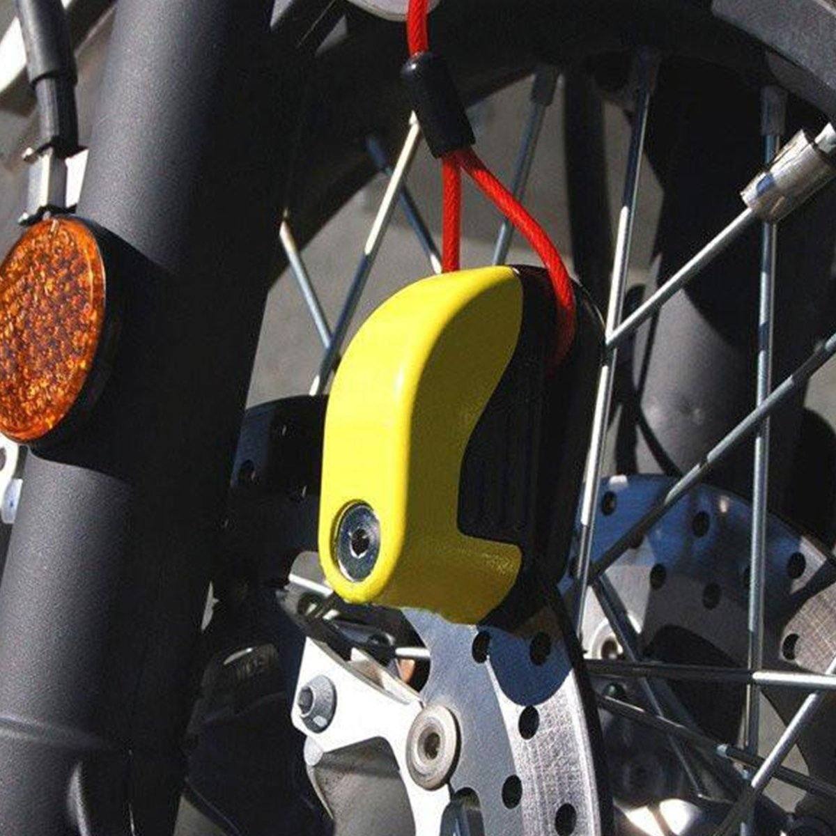 A close up of a Motorcycle Alarm Disc Lock with a yellow light attached to it.