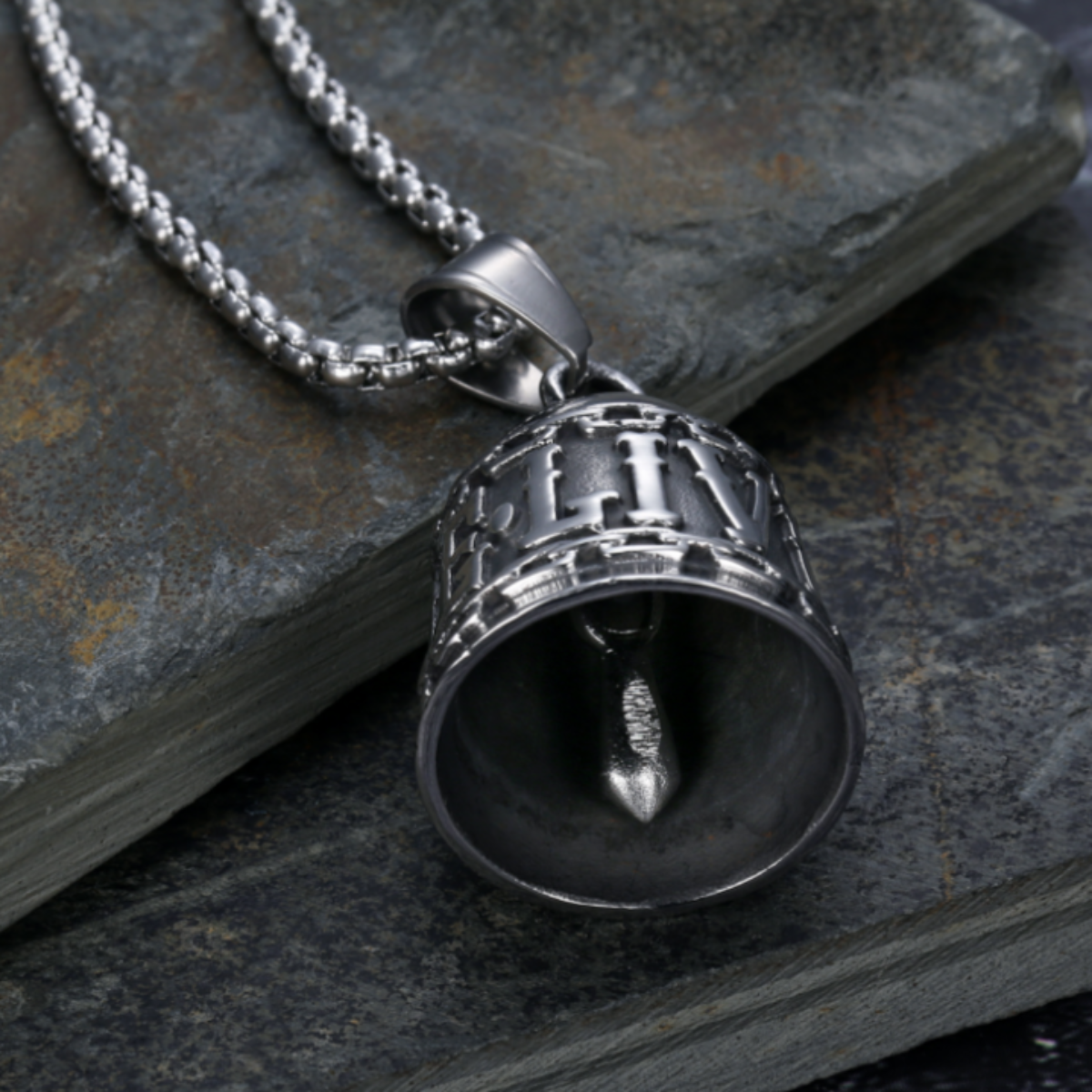 A Live to Ride Gremlin Bell with a chain on top of a rock.